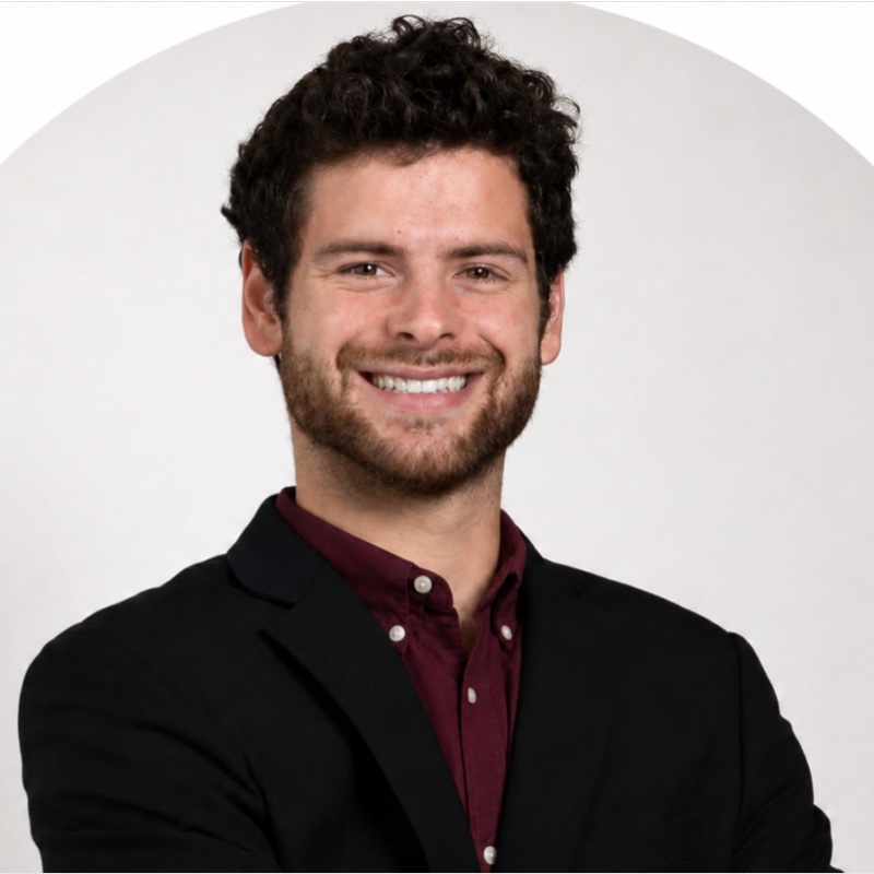 Bradley Minnich smiling in a black jacket and burgundy shirt.
